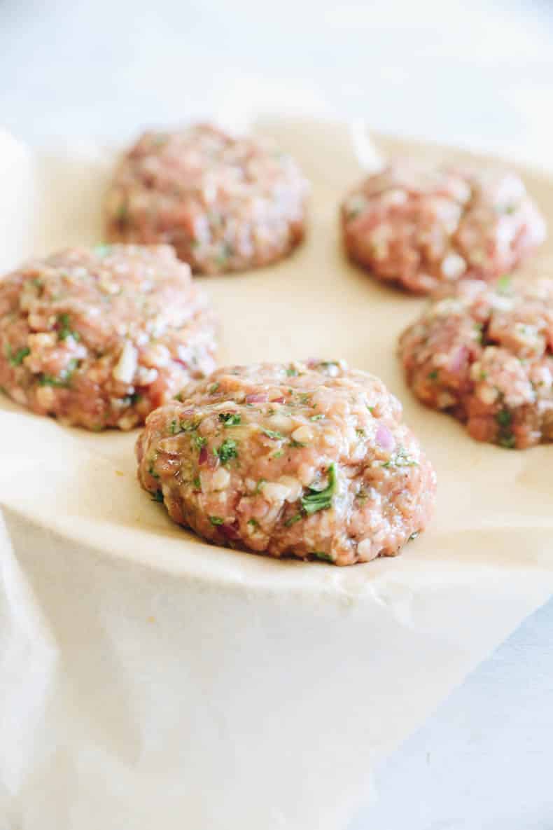 raw turkey patties on a plate with parchment paper