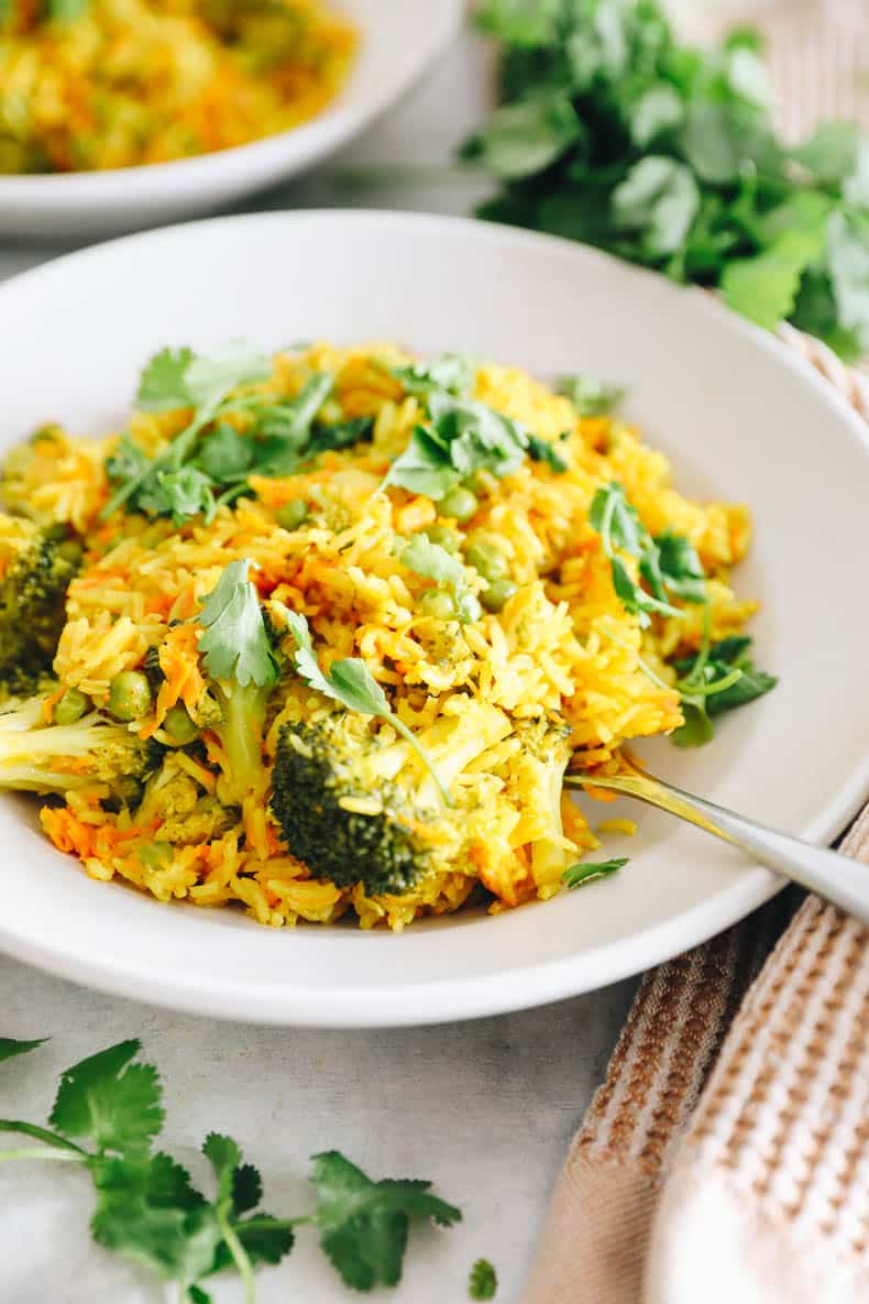 curry rice with broccoli and topped with cilantro in a white bowl.